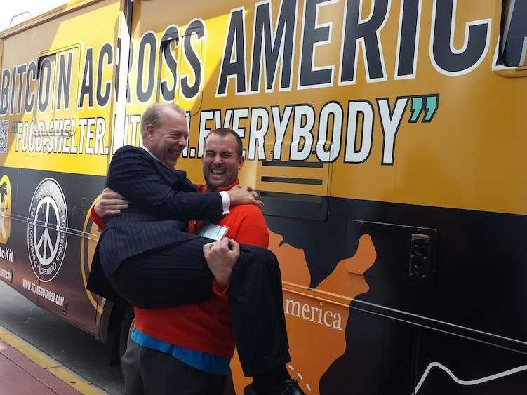 Sean's Outpost Founder Jason King lifts Jeffrey Tucker in front of the Bitcoins Across America RV.